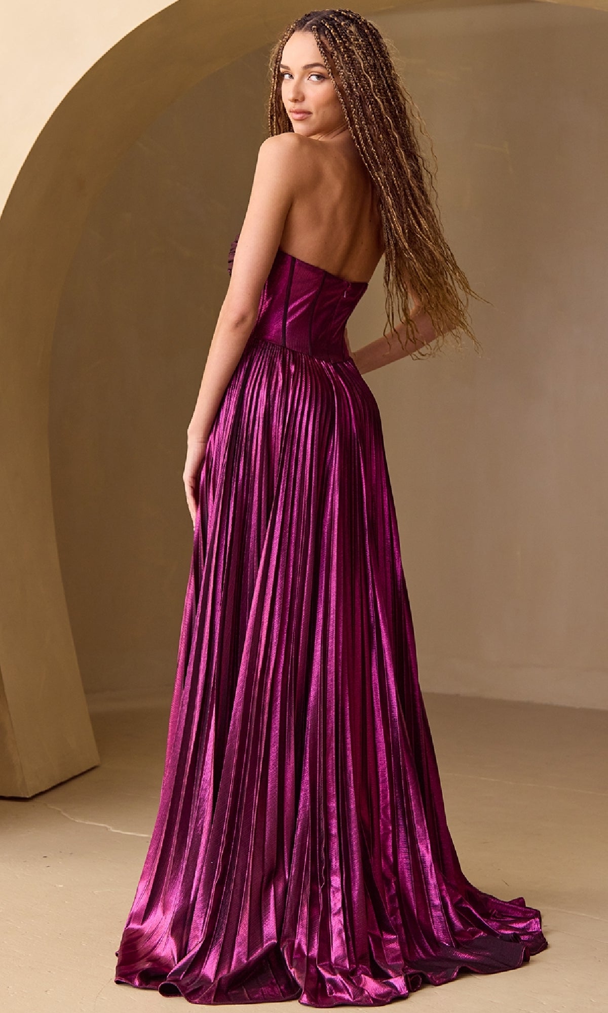 Woman modeling the back of a floor length plum purple dress standing in a beige room.